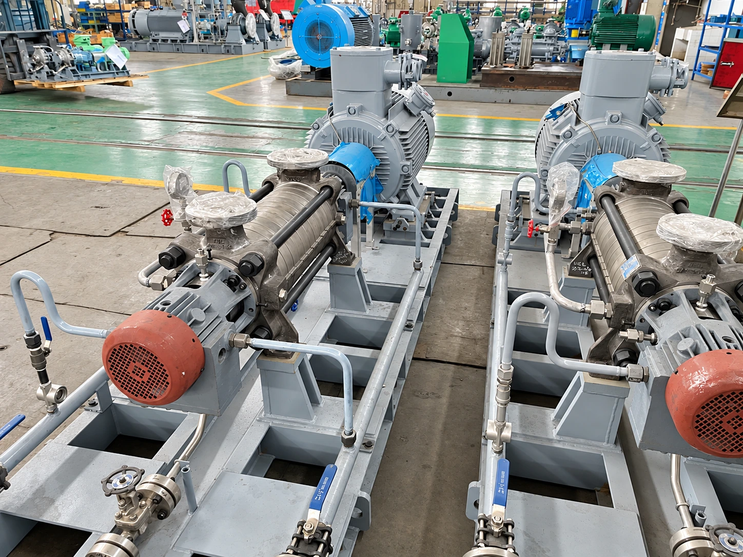 Long multistage pump assemblies arranged in the workshop.